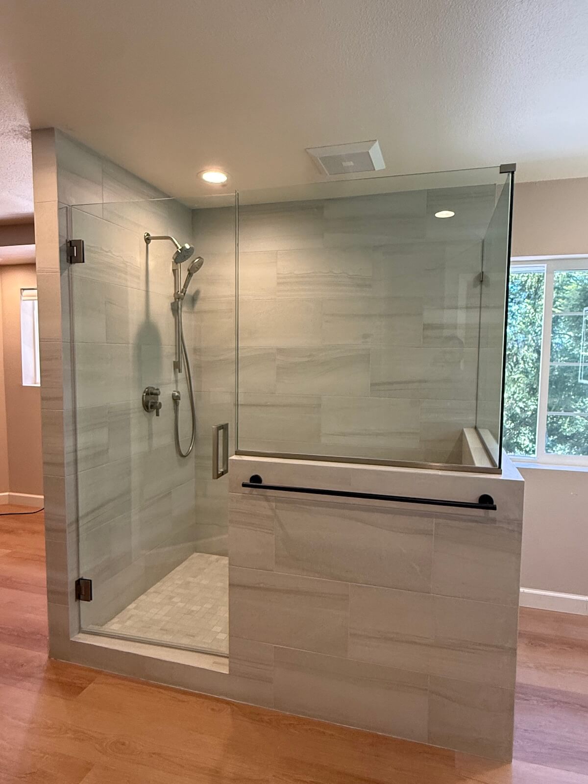 Glass-enclosed tile shower in remodeled primary bathroom