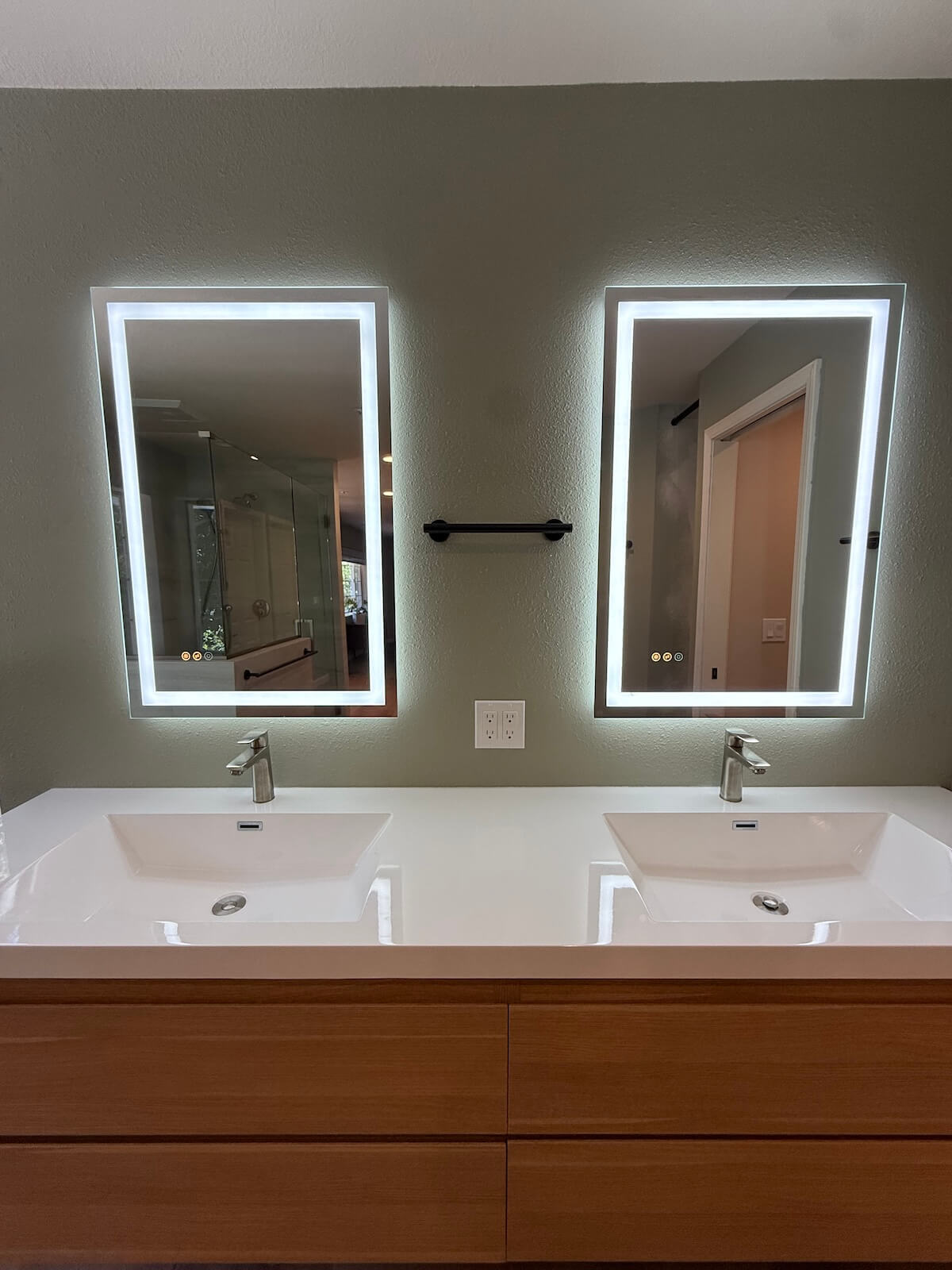 Backlit mirrors above dual sink vanity in remodeled bathroom