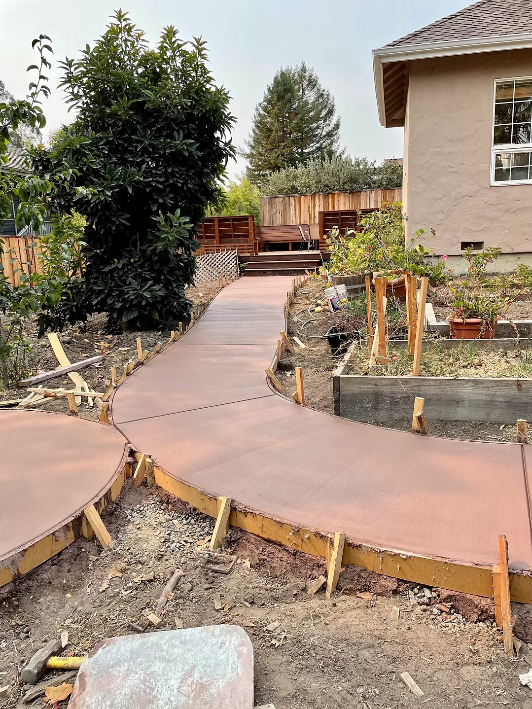 Curved concrete walkway poured through garden beds and raised planters