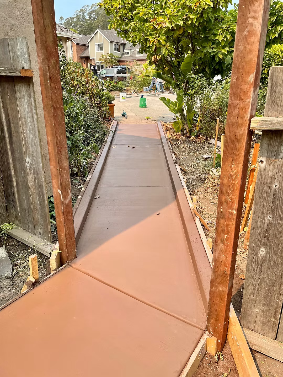 Concrete walkway leading through a wooden gate to the backyard patio area